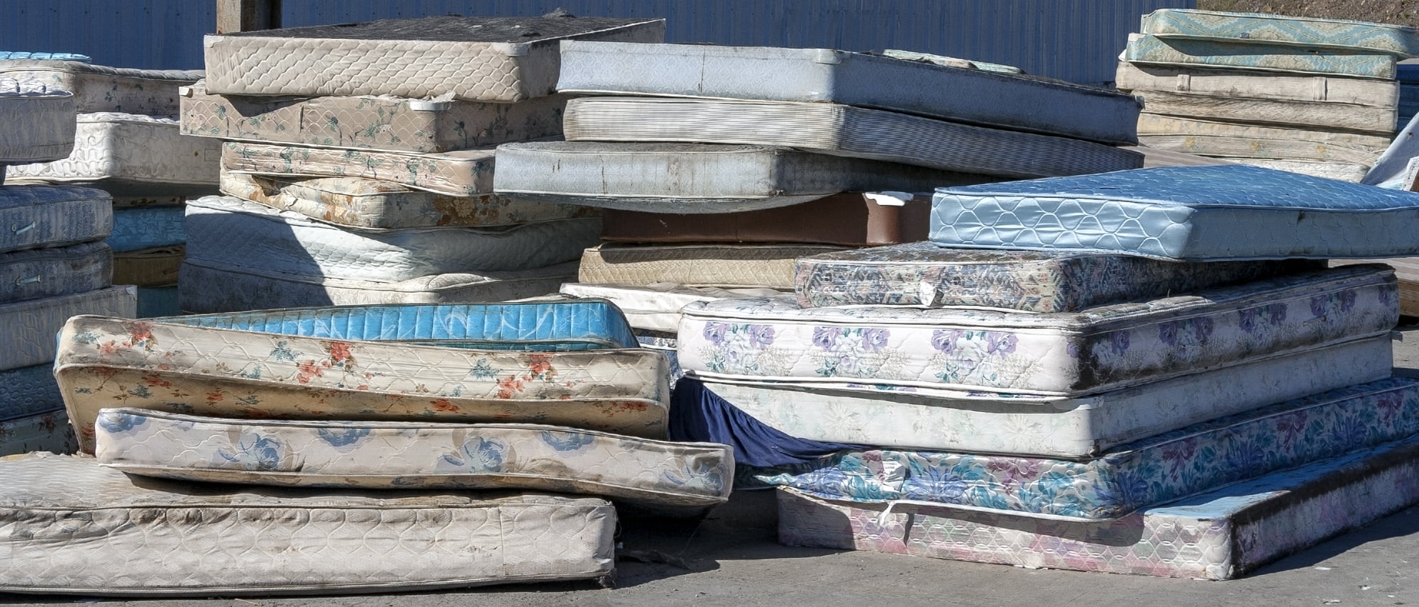 a pile of old mattresses at a recycling depot